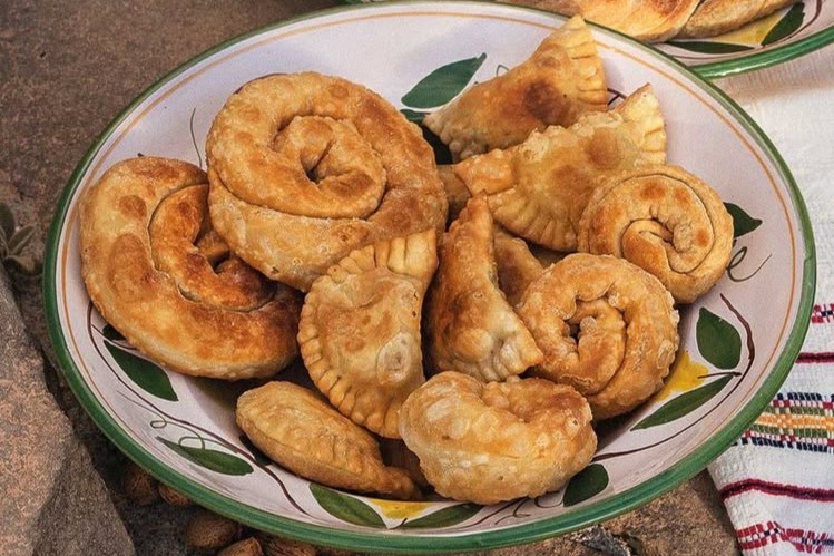 Μικρές σπειροειδείς χειροποίητες πίτες σε πιατέλα, με χρυσαφένιο ψήσιμο και σπιτική όψη.