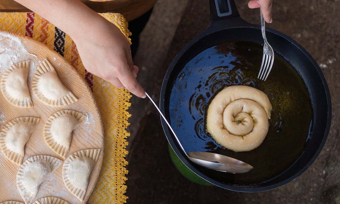 Χειροποίητο πλάσιμο στρογγυλής πίτας πάνω από τηγάνι, σε στάδιο παρασκευής πριν το ψήσιμο.
