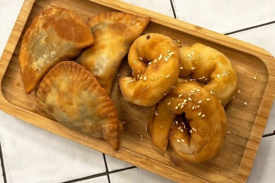 Ποικιλία από χειροποίητες παραδοσιακές πίτες και γλυκά σε ξύλινο δίσκο παρουσίασης.